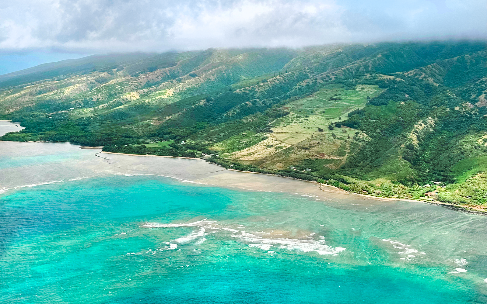 Aerial view of Maui coastline with lush green mountains and turquoise ocean during Hawaii helicopter tour.