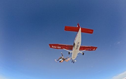 Skydivers jumping from a plane at 13000 ft against a clear blue sky.
