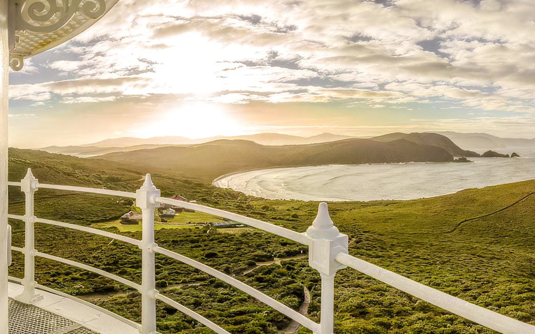 View from Bruny Island Lighthouse overlooking coastline and hills at sunset.