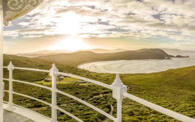 View from Bruny Island Lighthouse overlooking coastline and hills at sunset.
