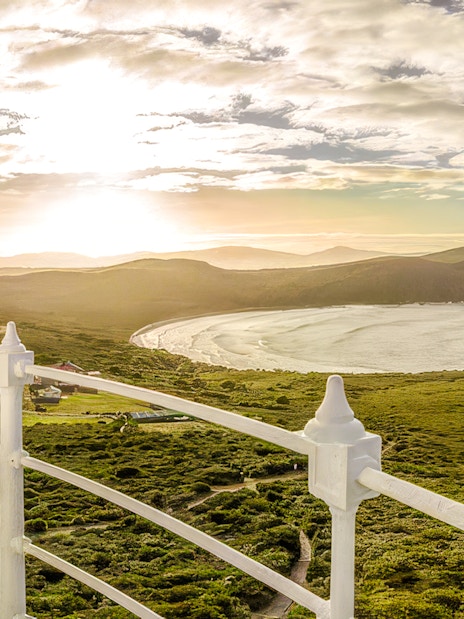 View from Bruny Island Lighthouse overlooking coastline and hills at sunset.