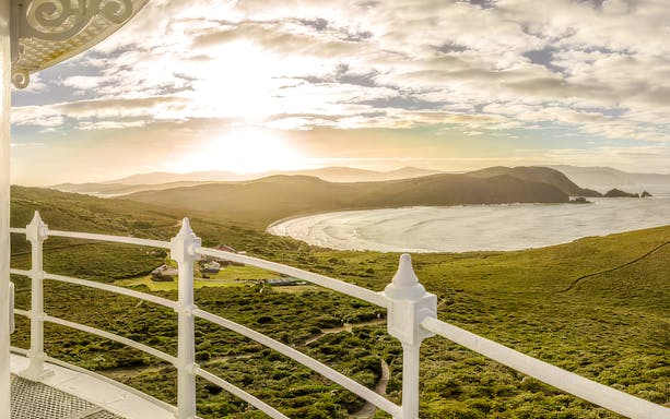 View from Bruny Island Lighthouse overlooking coastline and hills at sunset.