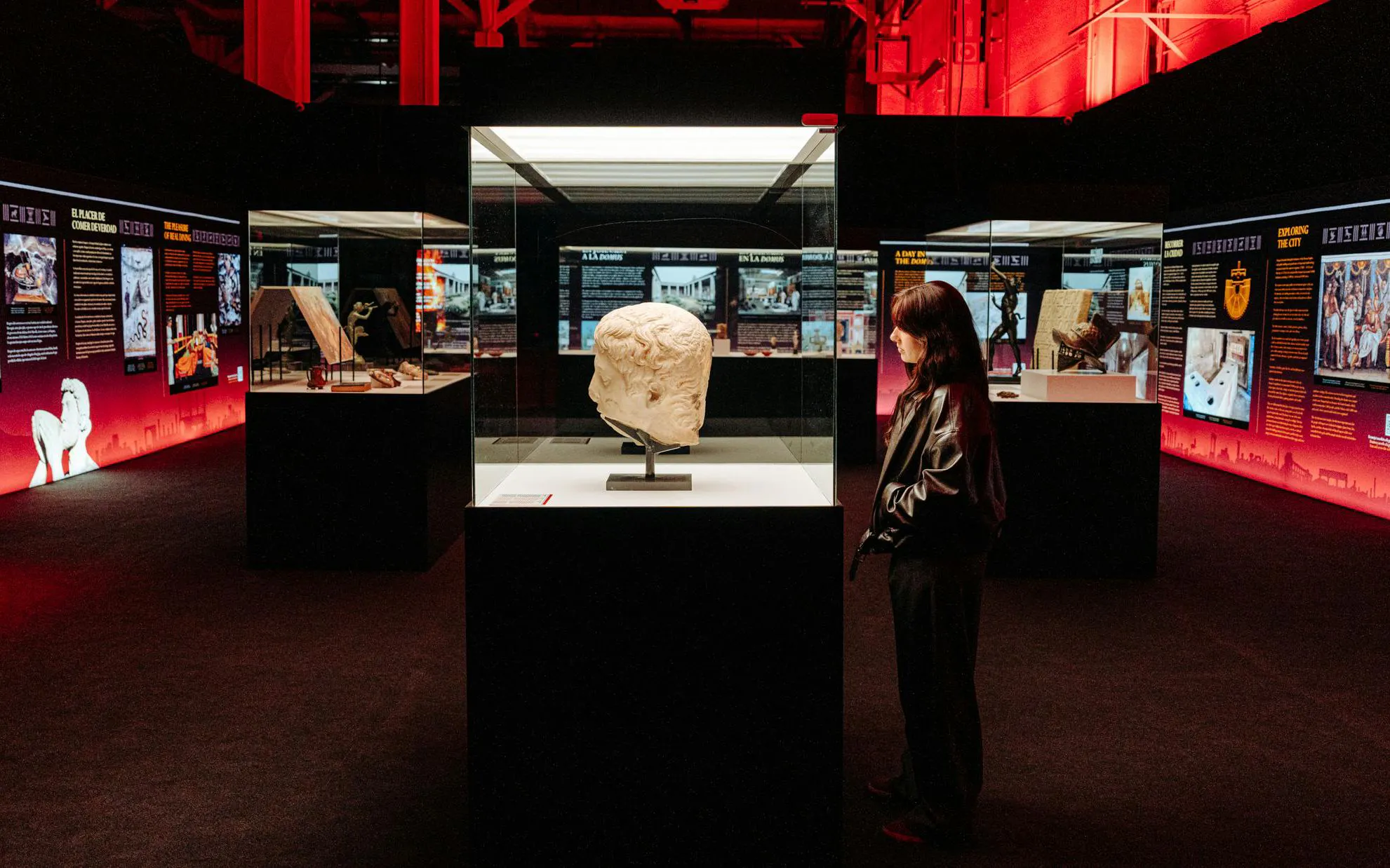 Pompeia exhibit at IDEAL Barcelona with visitor viewing ancient sculpture.