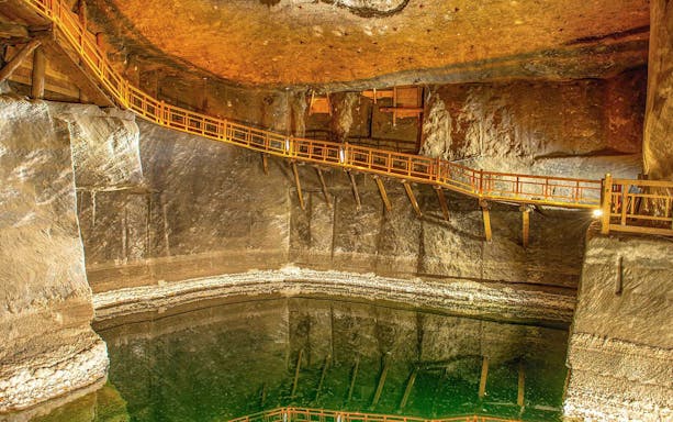 Wieliczka Salt Mine underground chamber with wooden walkway and reflective water surface.