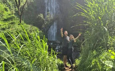 Hikers at Materuni Waterfall surrounded by lush greenery, Arusha tour.