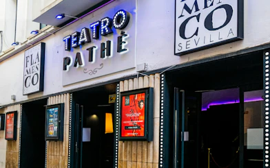Entrance of Teatro Flamenco Sevilla with illuminated signs and posters.