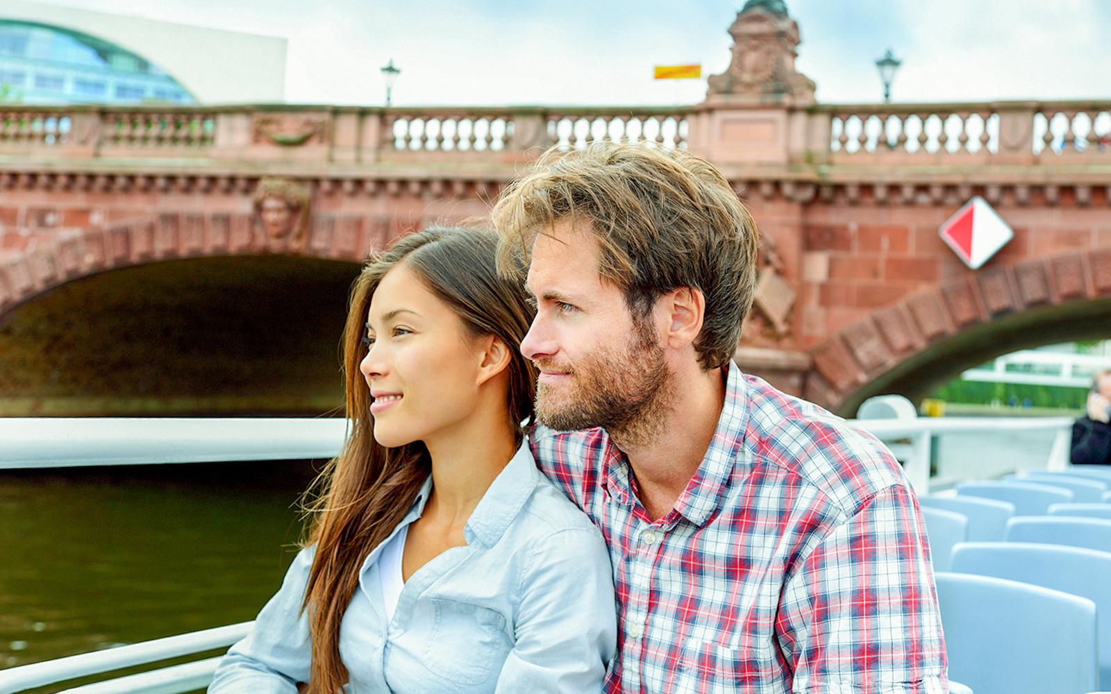 Couple enjoying a scenic view on a Berlin city cruise under a historic bridge.