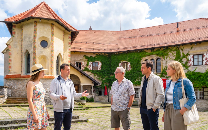 Group tour in the courtyard of Bled Castle, Slovenia, with guide explaining history.