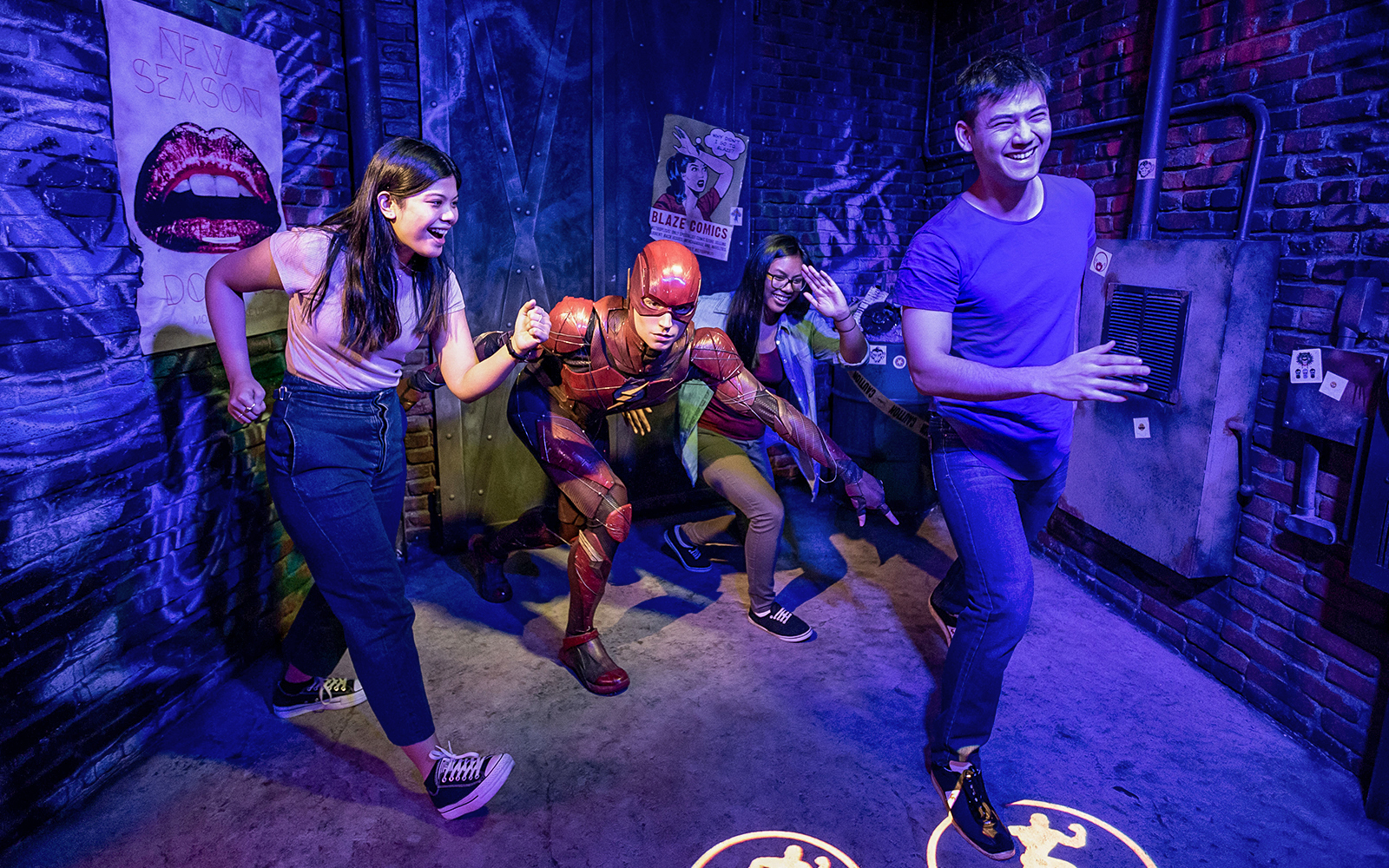 Visitors posing with Flash wax statue at Madame Tussauds.