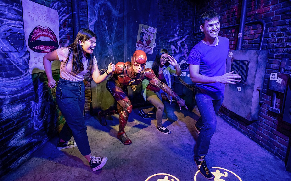 Visitors posing with Flash wax statue at Madame Tussauds.