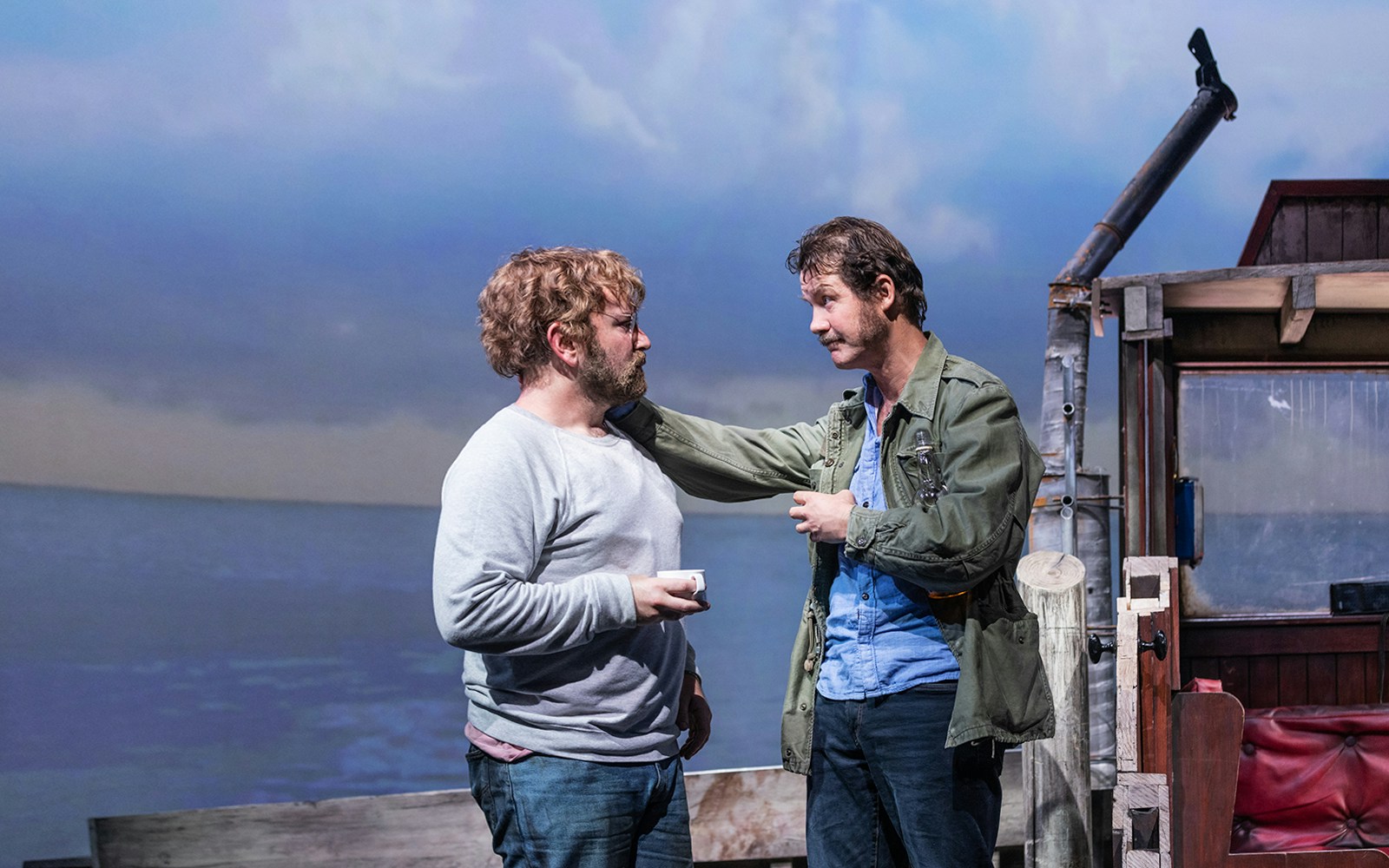 Actors on stage in "The Shark is Broken" with ocean backdrop.