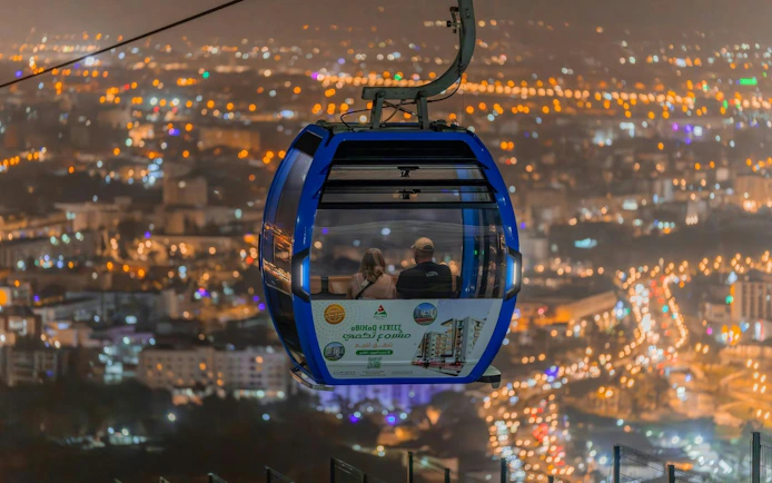 Nighttime view from a cable car over city lights, round-trip ticket experience.