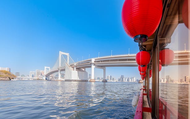 Yakatabune boat with red lanterns cruising Tokyo Bay near Rainbow Bridge.