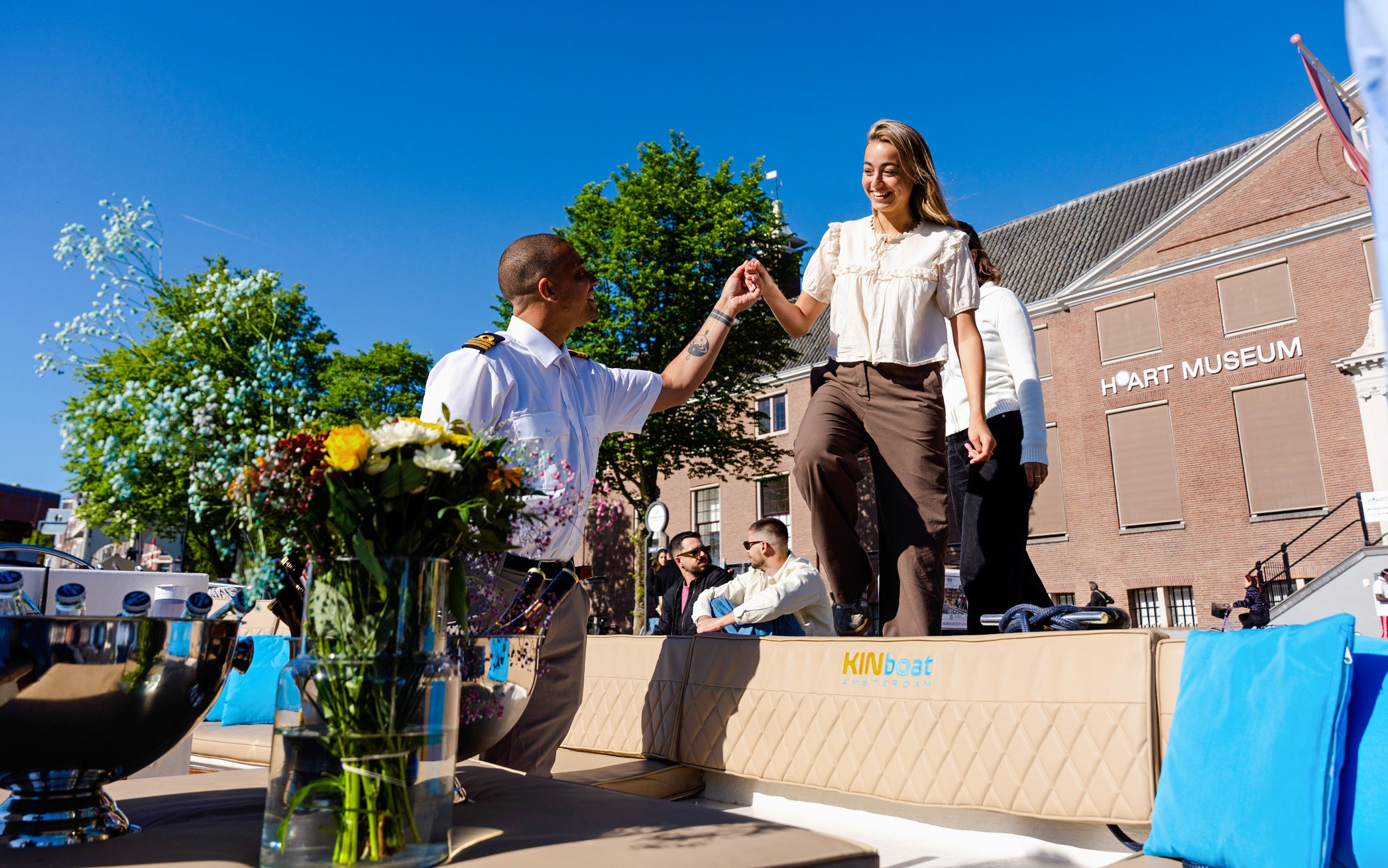 Guests boarding an open boat cruise in Amsterdam with a guide assisting near H'ART Museum.