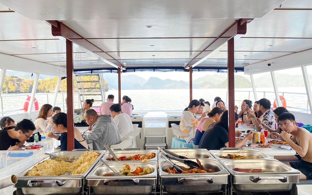 People dining on a Langkawi sunset cruise with buffet and scenic ocean view.