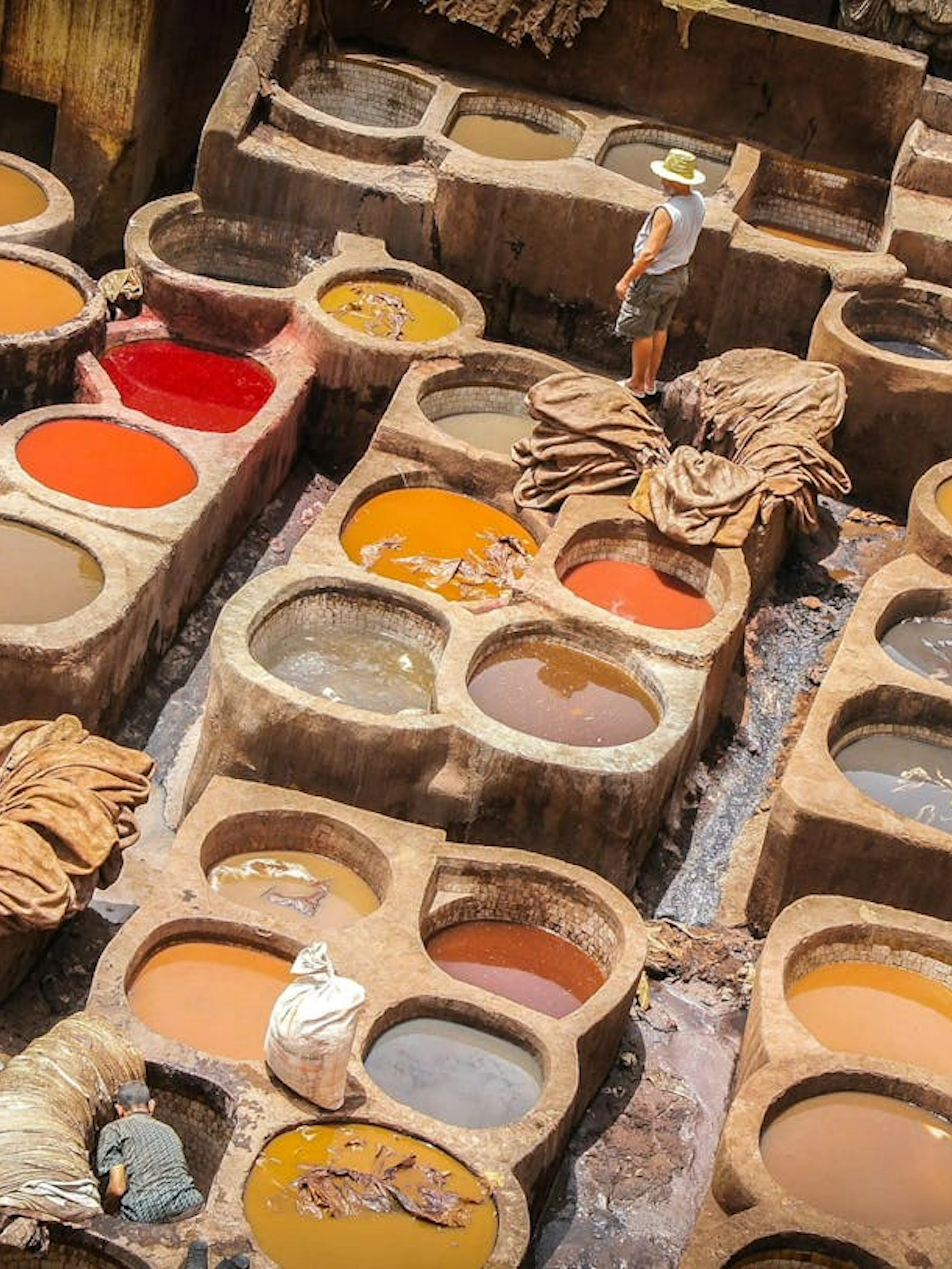 Traditional tannery in Fes with colorful dye vats and workers processing leather.