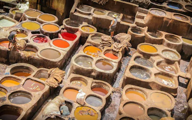 Traditional tannery in Fes with colorful dye vats and workers processing leather.
