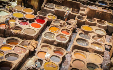 Traditional tannery in Fes with colorful dye vats and workers processing leather.