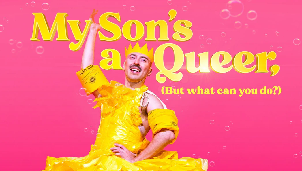 Performer in yellow costume with text "My Son's a Queer, (But What Can You Do?)" on pink background, Westend.