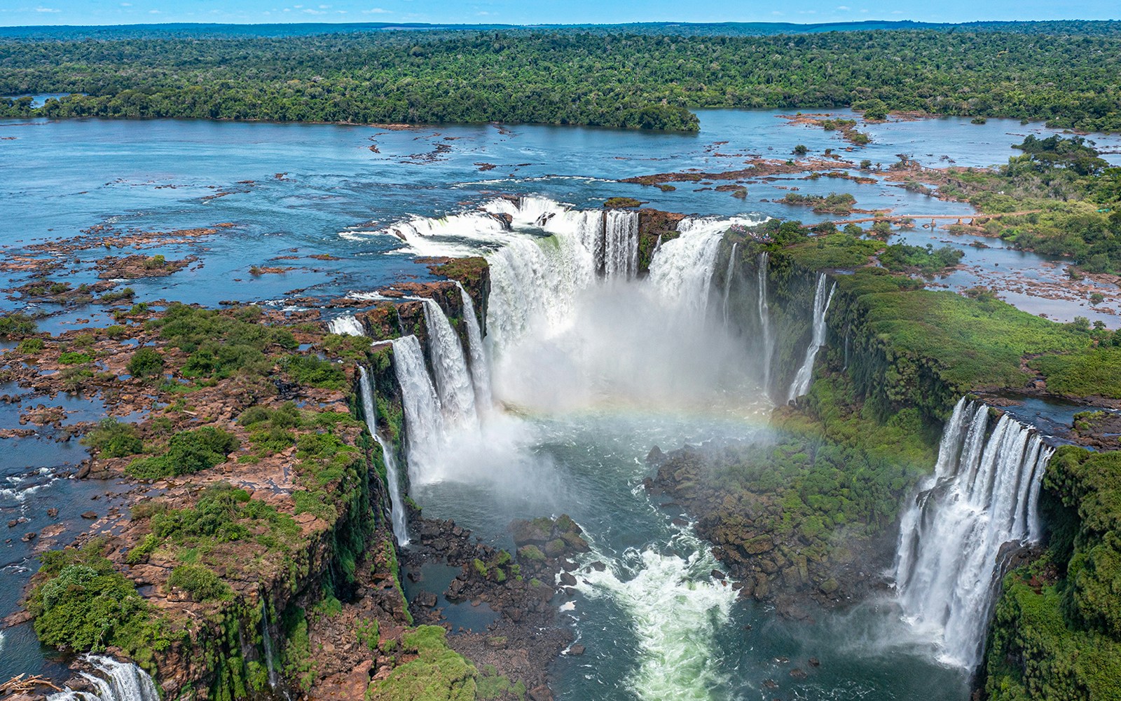 Aerial view of Iguazu Falls from a helicopter ride, showcasing cascading waterfalls and lush rainforest.