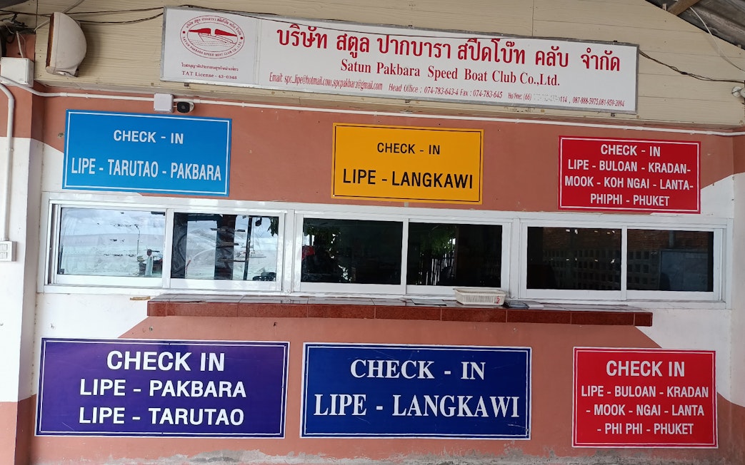 Check-in signs for ferry routes between Koh Lipe, Langkawi, and other destinations.