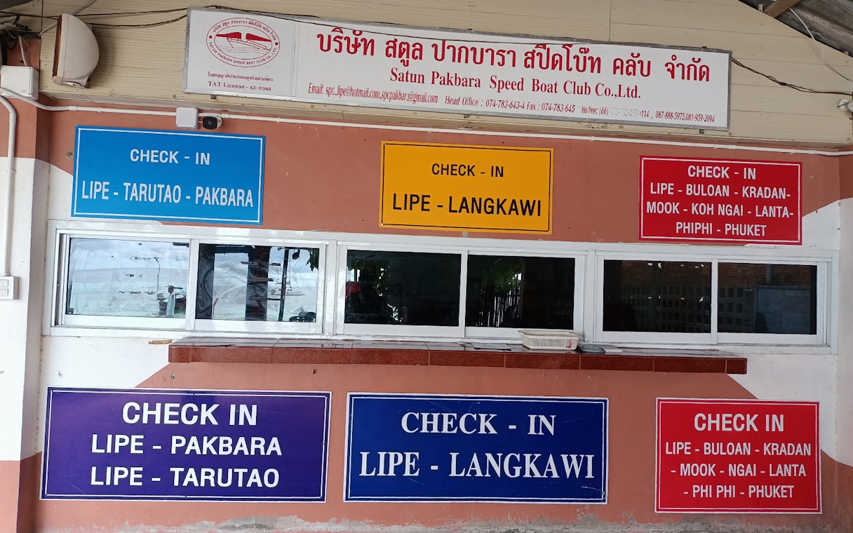 Check-in signs for ferry routes between Koh Lipe, Langkawi, and other destinations.