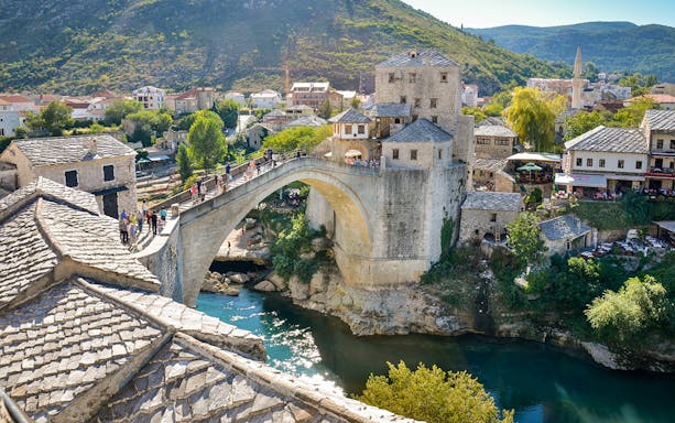 Mostar Bridge spanning the Neretva River with surrounding historic buildings in Mostar, Bosnia and Herzegovina.