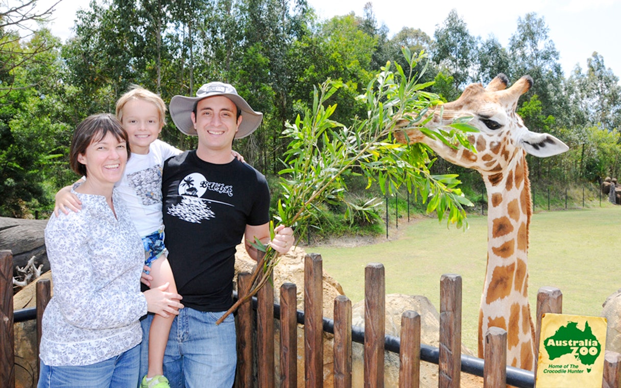 Tourists with a giraffe at Australia Zoo.