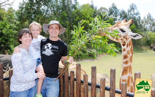 Tourists with a giraffe at Australia Zoo.