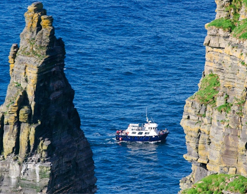 Boat navigating between sea stacks near Cliffs of Moher, Ireland.
