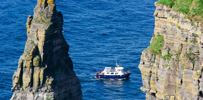 Boat navigating between sea stacks near Cliffs of Moher, Ireland.