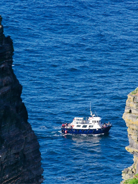 Boat navigating between sea stacks near Cliffs of Moher, Ireland.