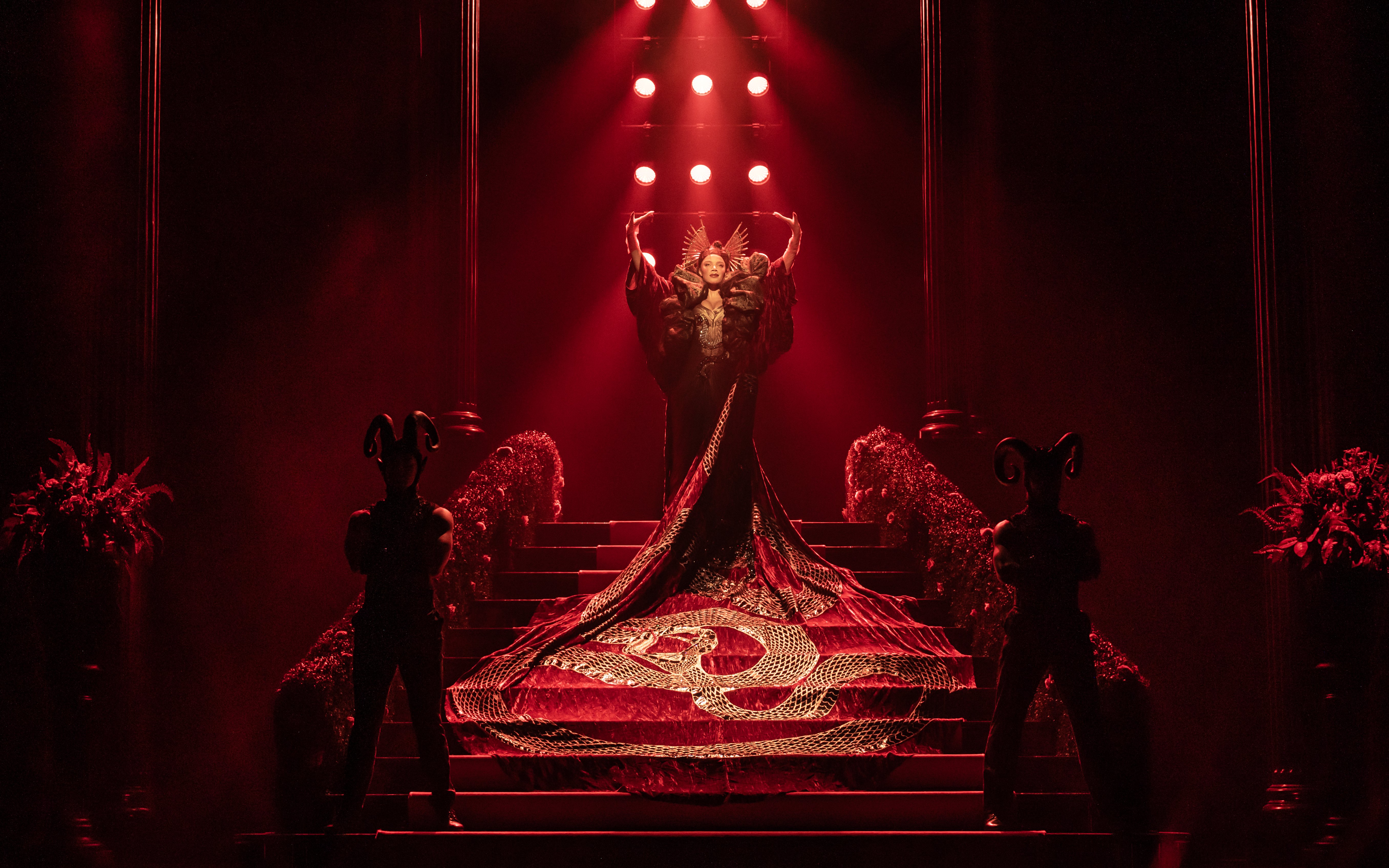 Stage performance of The Devil Wears Prada West End show with dramatic red lighting.