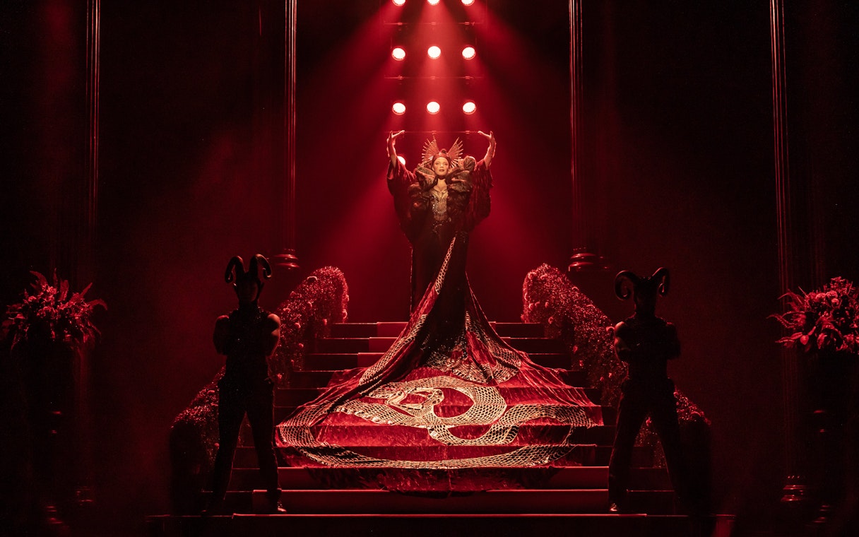 Stage performance of The Devil Wears Prada West End show with dramatic red lighting.