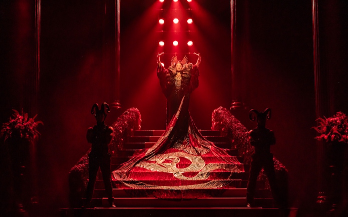 Stage performance of The Devil Wears Prada West End show with dramatic red lighting.