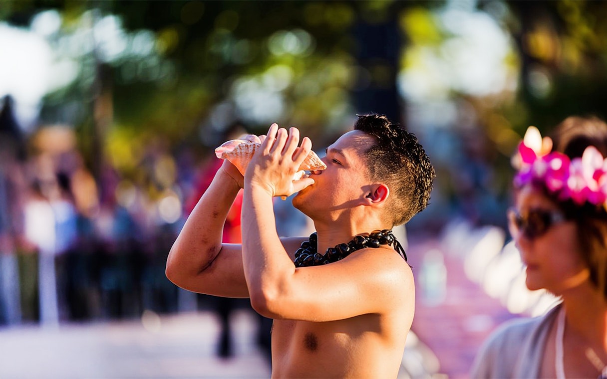 Blowing conch shell to start ceremonies at Paradise Cove Luau, Hawaii.