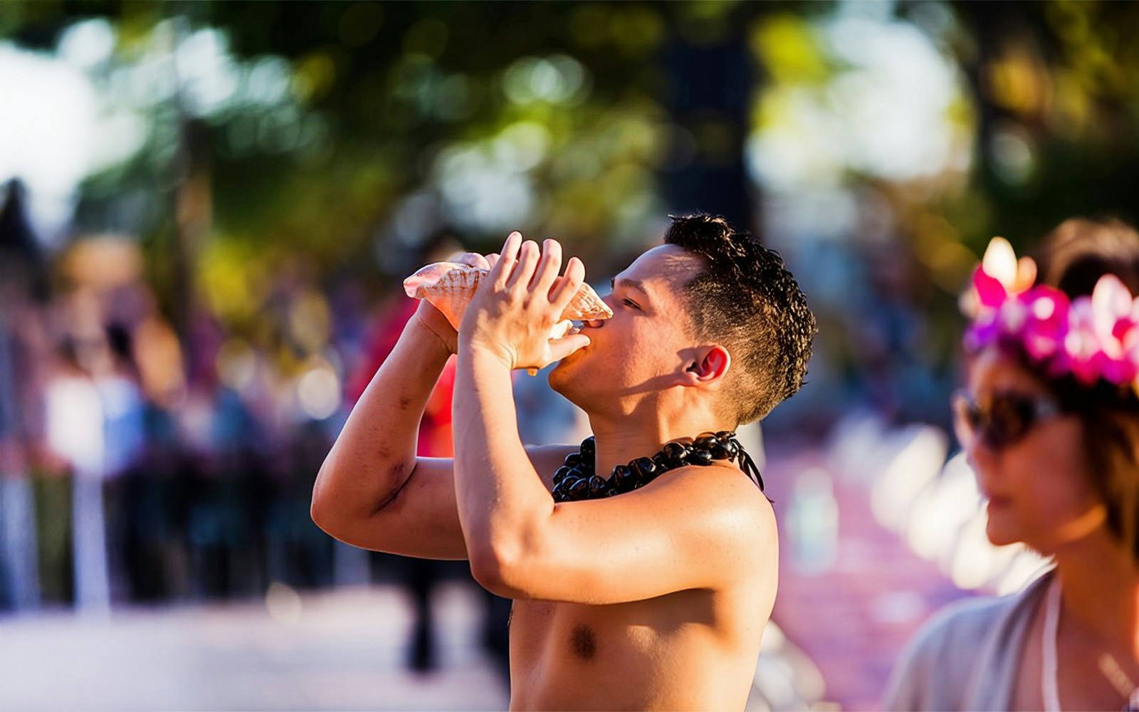 Blowing conch shell to start ceremonies at Paradise Cove Luau, Hawaii.
