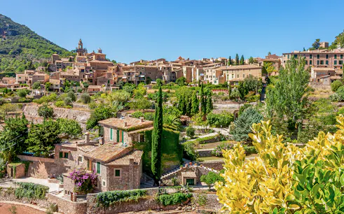 Valldemossa village view with stone houses and lush greenery, Mallorca, Spain.