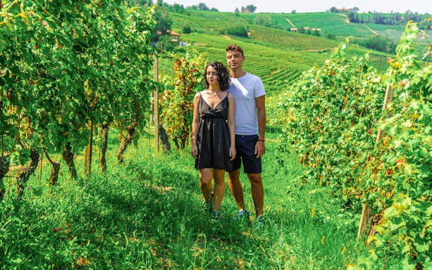 Couple walking through vineyards in Langhe, Italy, during a Vespa tour.