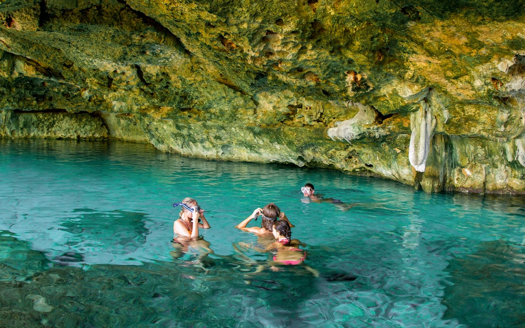 Tourists snorkeling in a cenote, Yucatan Peninsula, Mexico, surrounded by limestone formations.