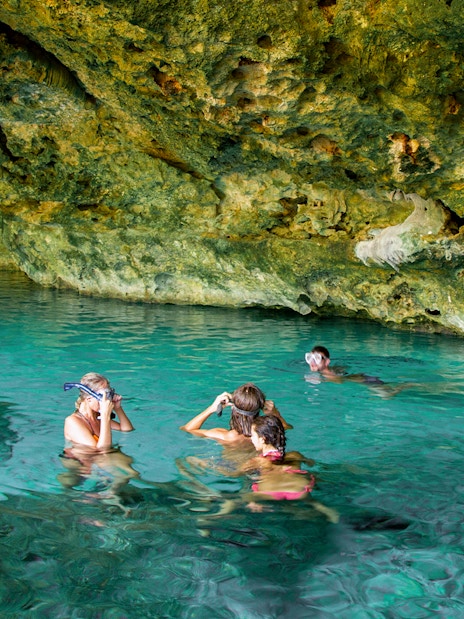 Tourists snorkeling in a cenote, Yucatan Peninsula, Mexico, surrounded by limestone formations.