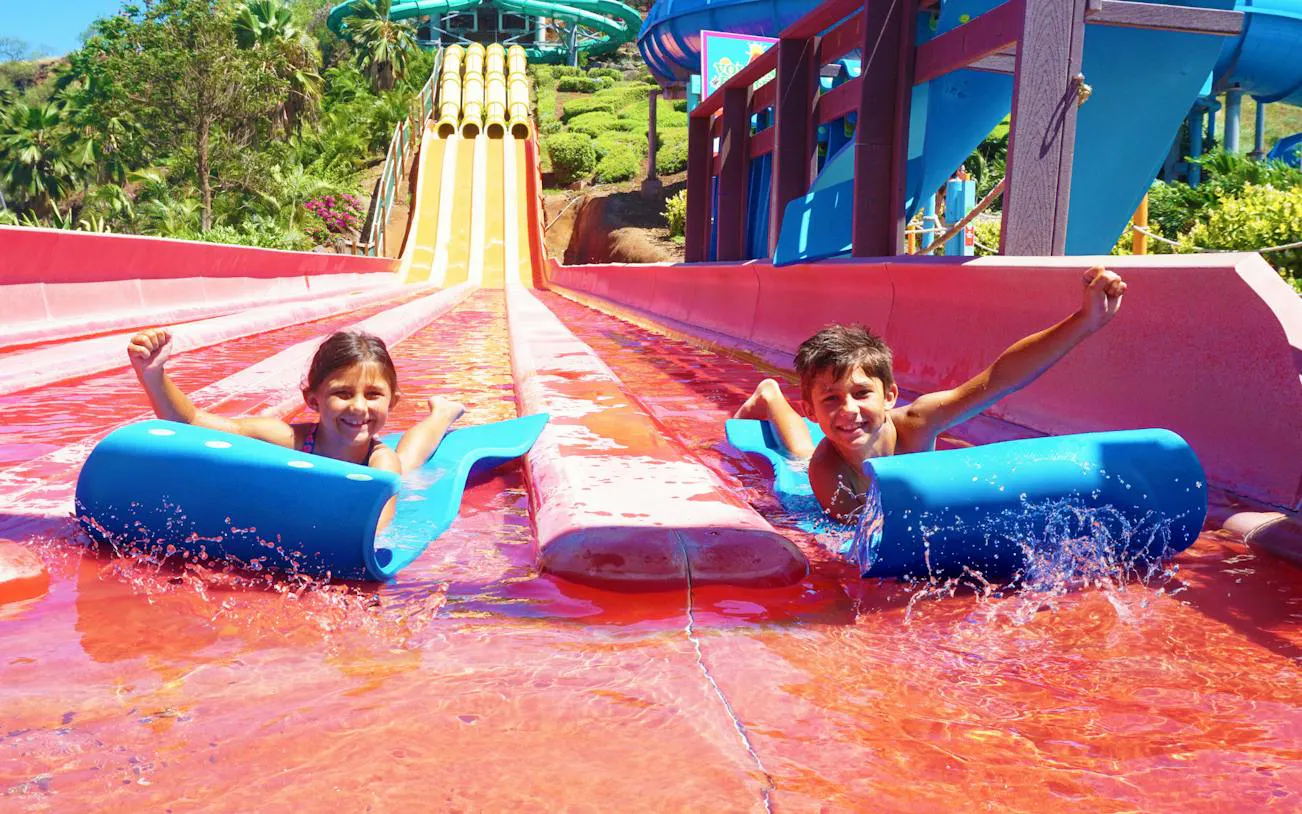 Children enjoying a water slide at Wet 'n' Wild Hawaii, Oahu.