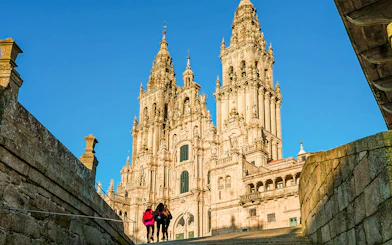 Santiago De Compostela Cathedral with visitors under a clear blue sky.