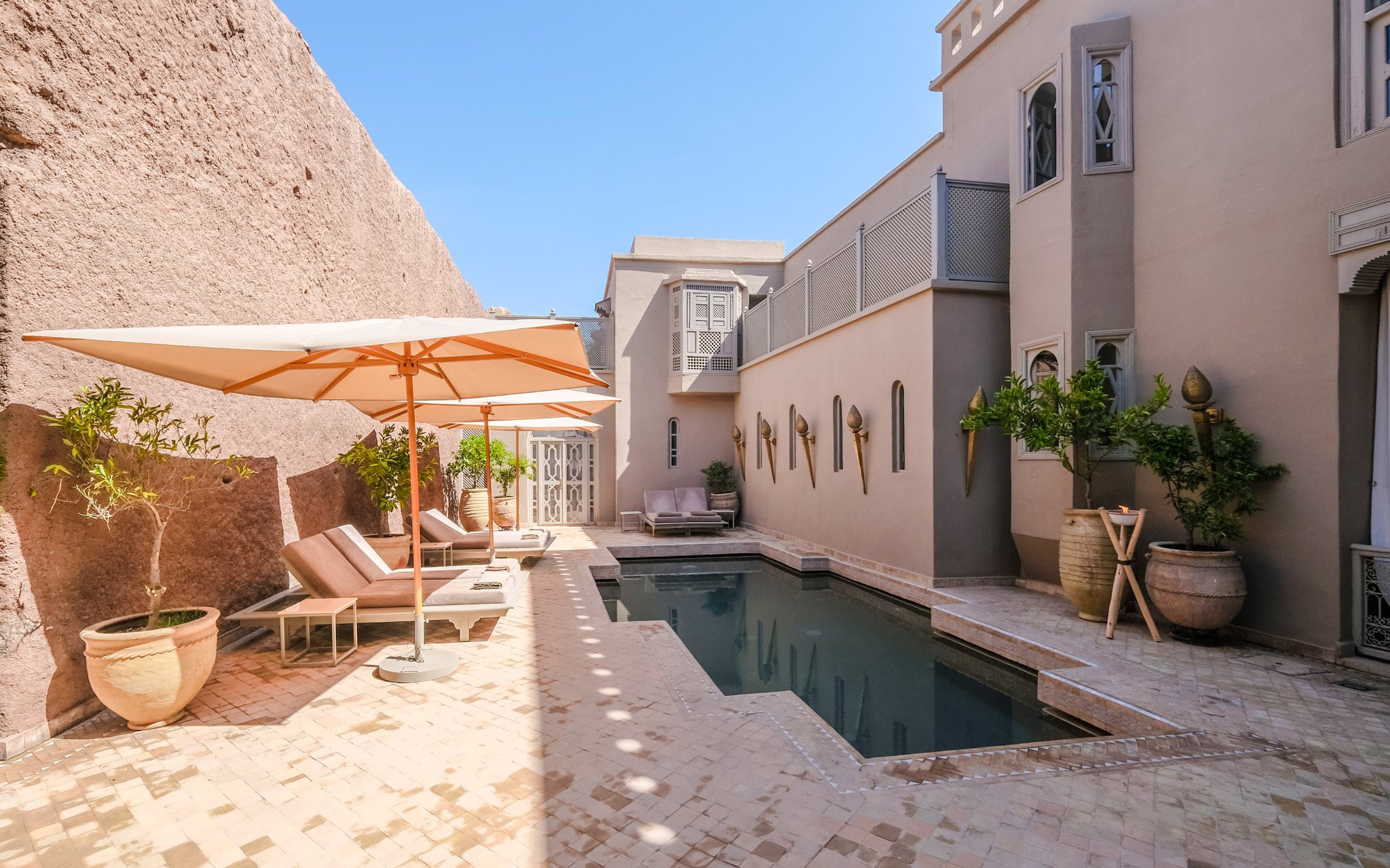 Outdoor pool area with sun loungers and umbrellas at a luxury steam hammam and spa.