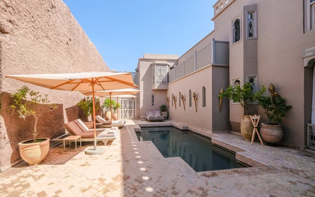 Outdoor pool area with sun loungers and umbrellas at a luxury steam hammam and spa.