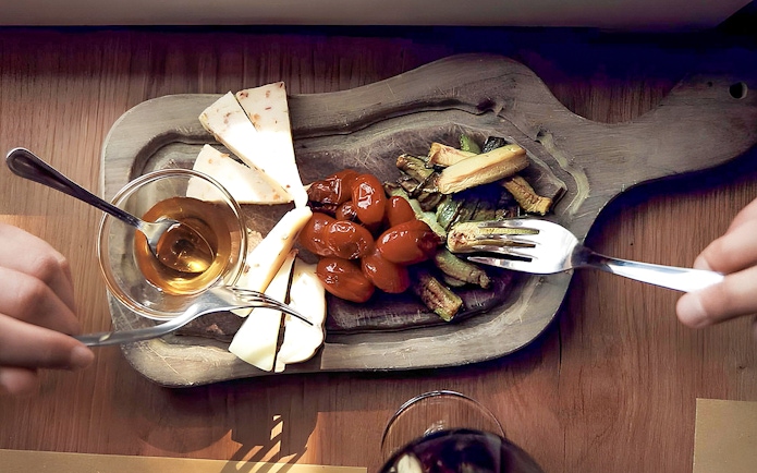 Cheese, tomatoes, and vegetables on a wooden platter during Chianti wine and olive oil tour.
