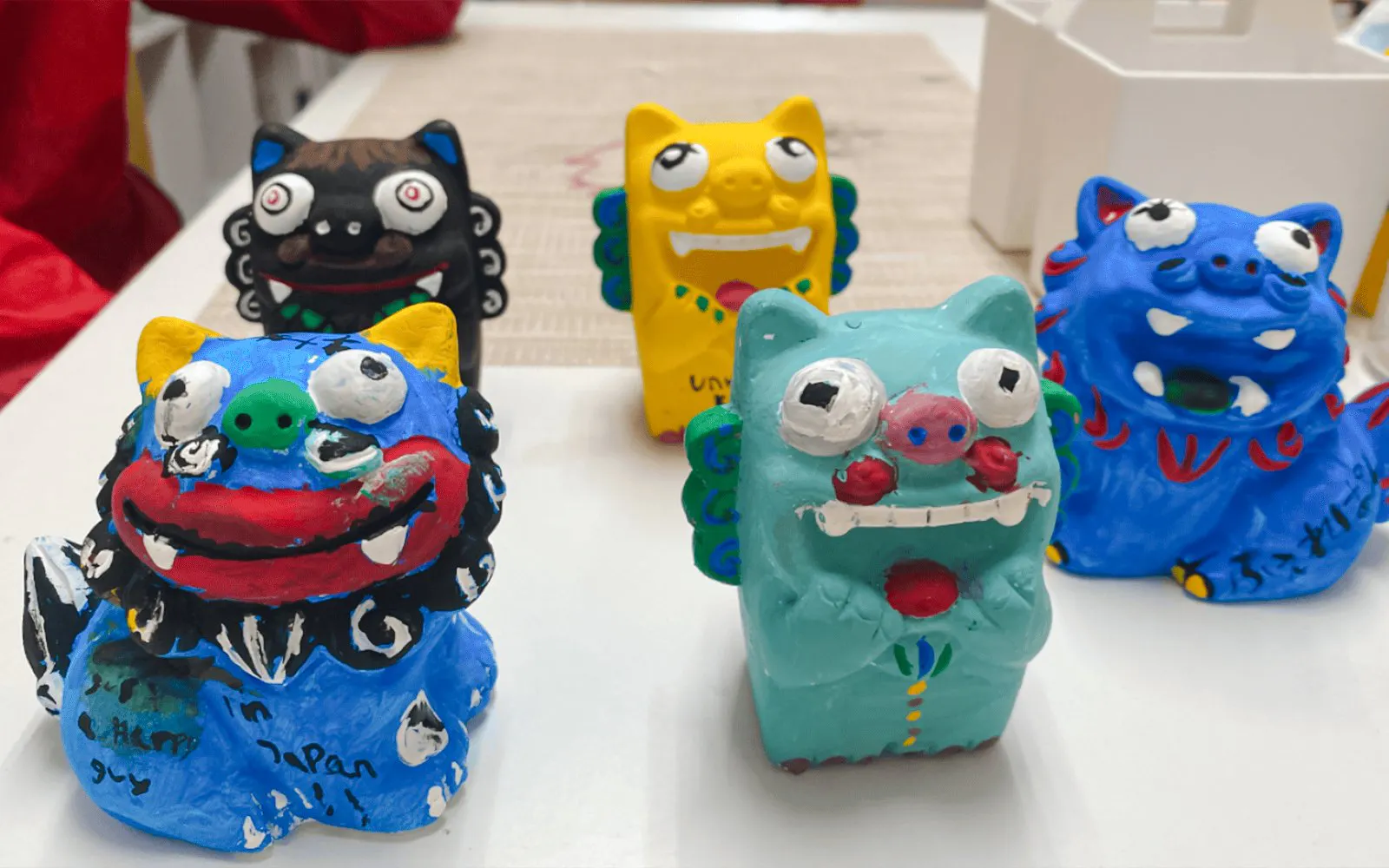 Colorful terracotta Shisa statues, traditional Okinawan guardian deities, displayed on a table.