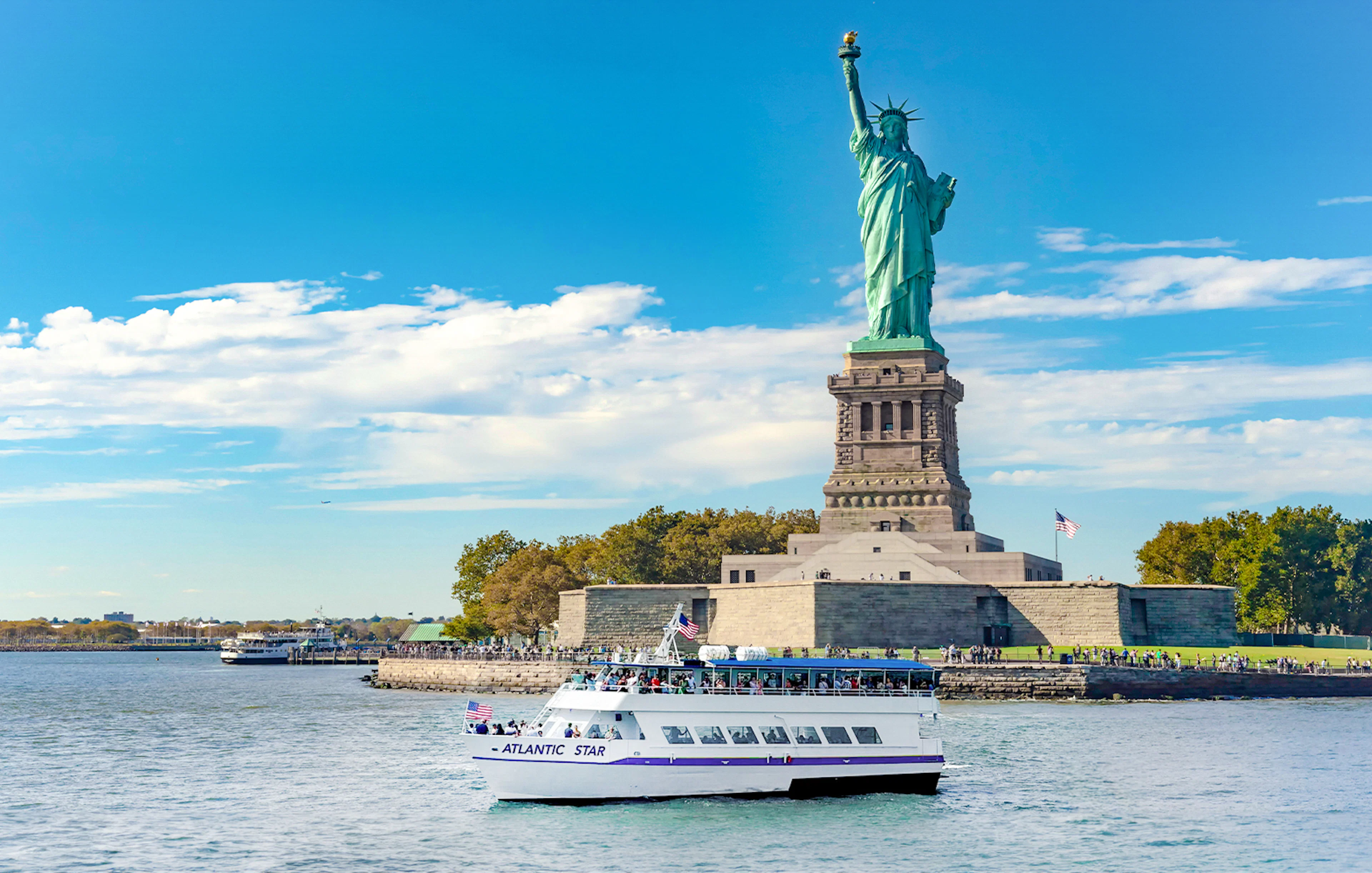 Tourists on a boat near the Statue of Liberty, New York, on a sunny day.