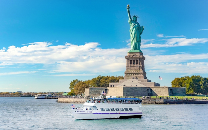 Tourists on a boat near the Statue of Liberty, New York, on a sunny day.