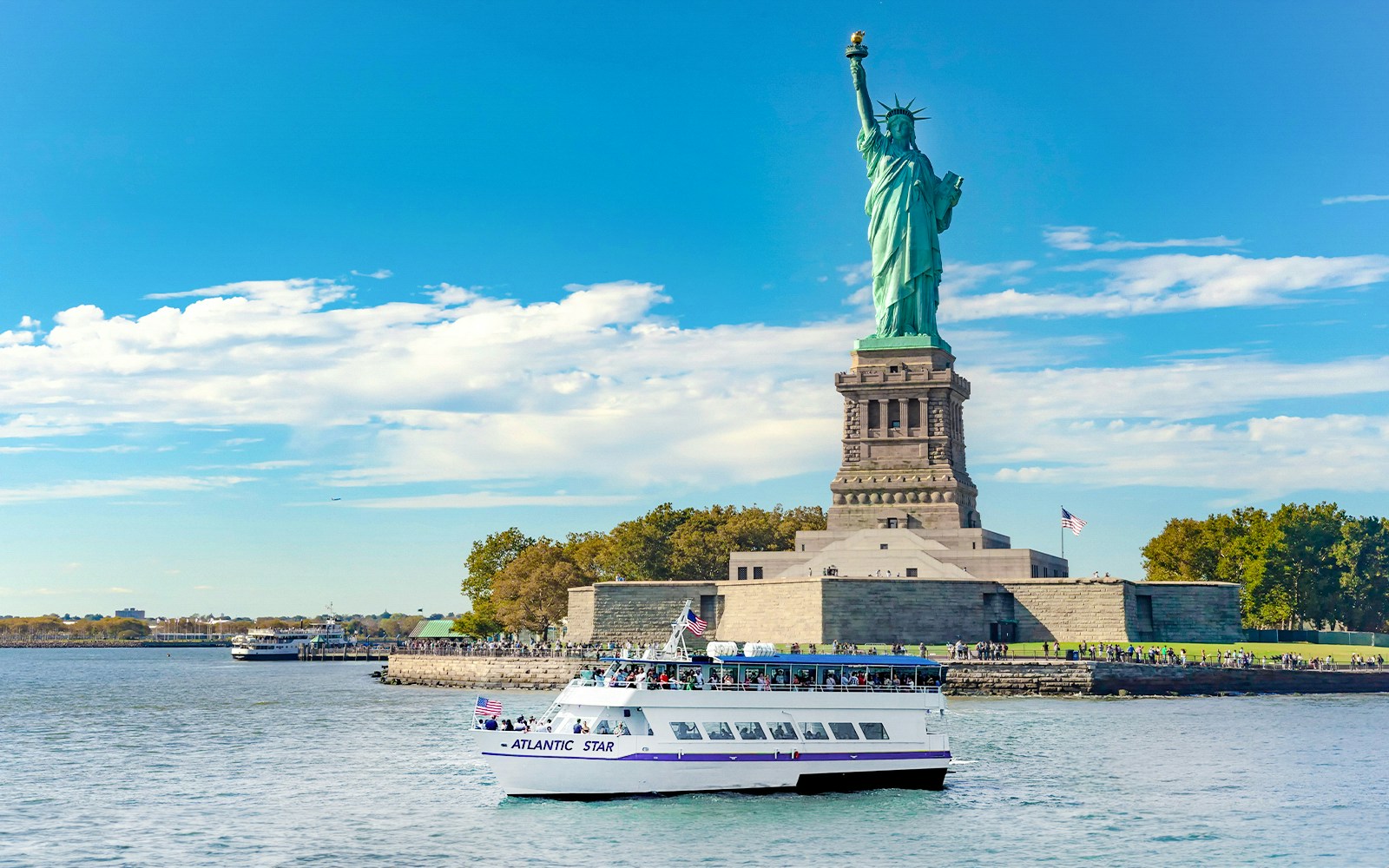 Tourists enjoying a combo deal saving 24% on a sunny day at the Statue of Liberty, New York